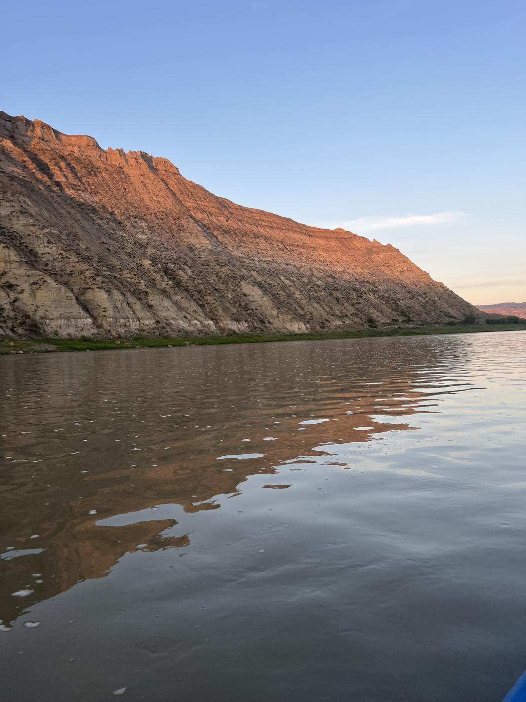 Badlands cliff glowing orange at sunset above the Missouri River