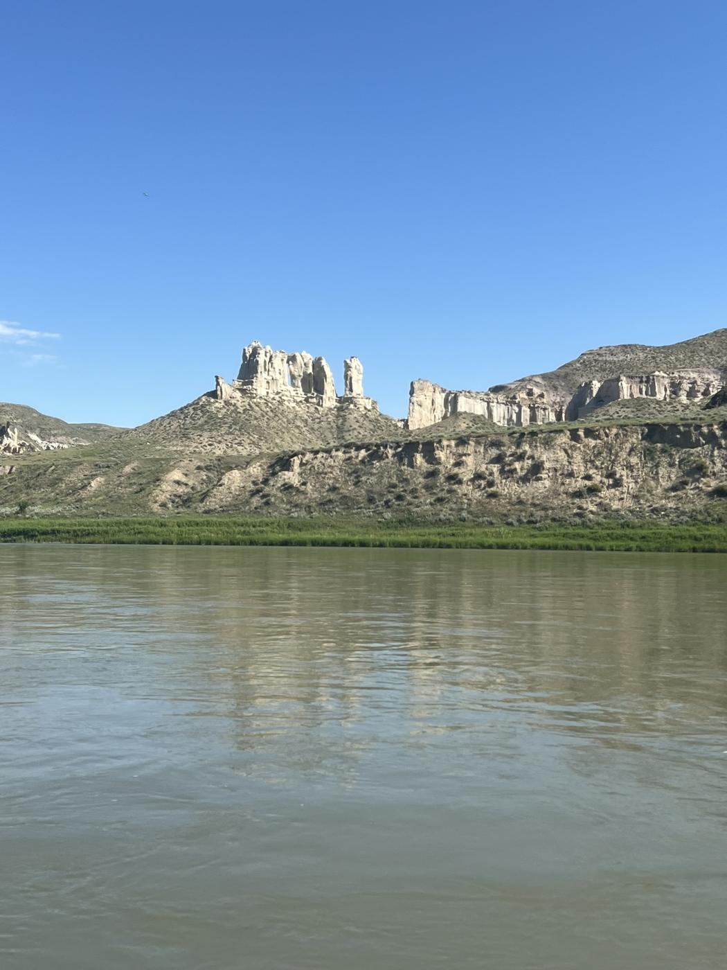 Pale sandstone towers and castle-like formations above a wide green river